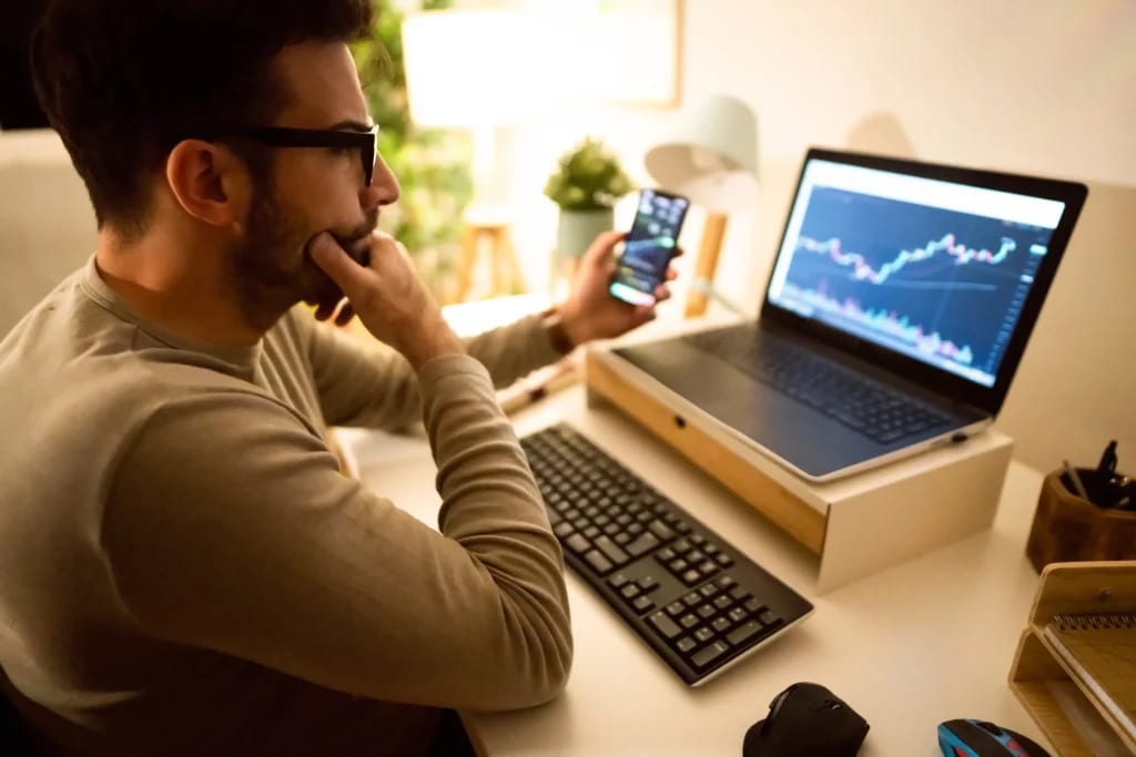 investor at laptop with smartphone 061322