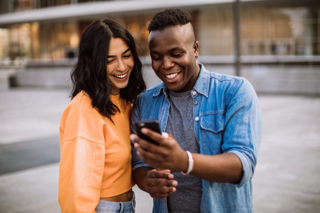 happy couple outdoors staring at phone