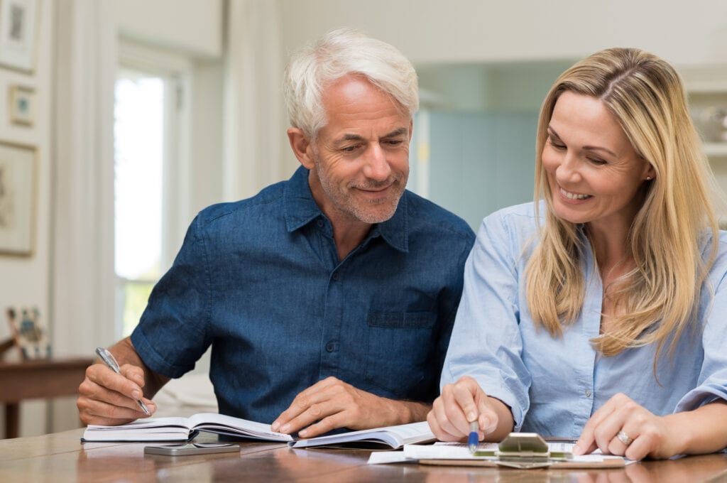 mature couple discussing finances with pens and paper