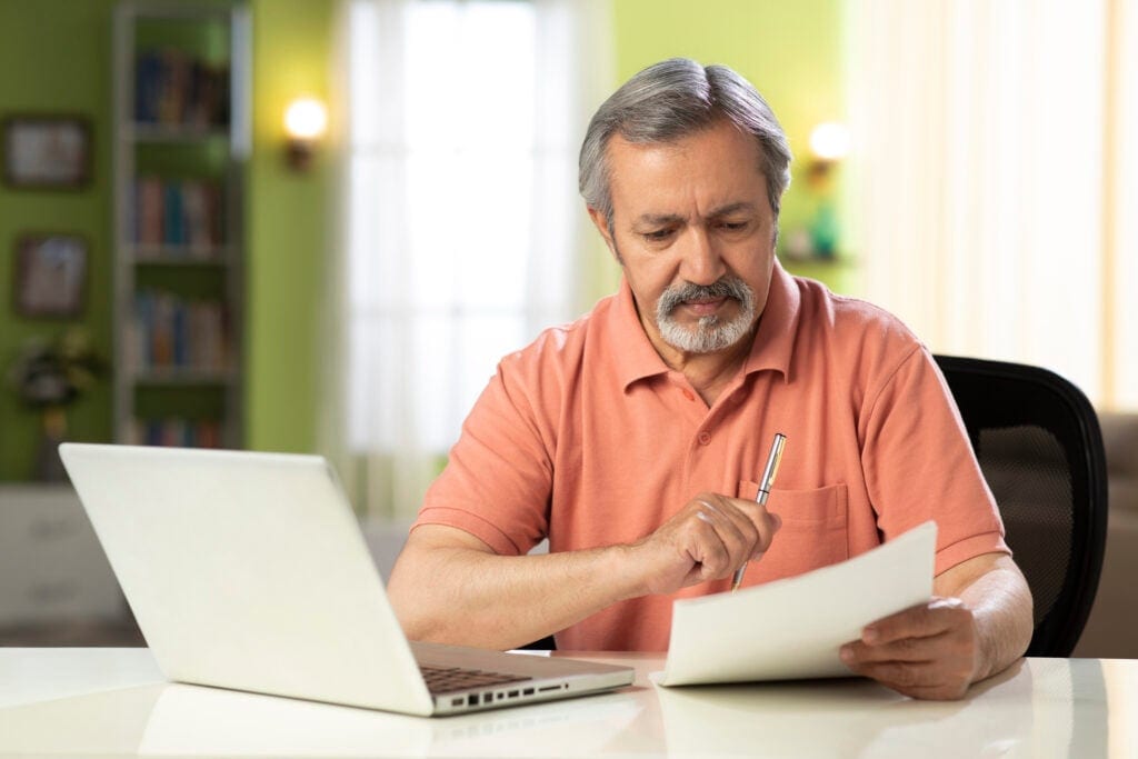 mature person holding pen and looking at document SSdMn