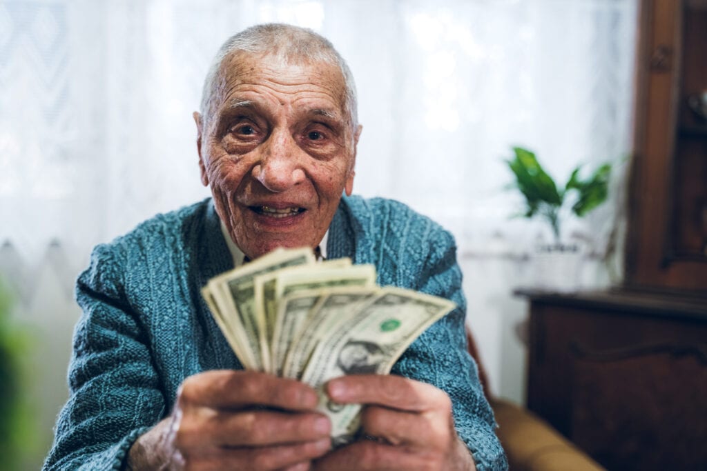senior man counting cash money bills social security retire invest inflation cola getty LMwDR