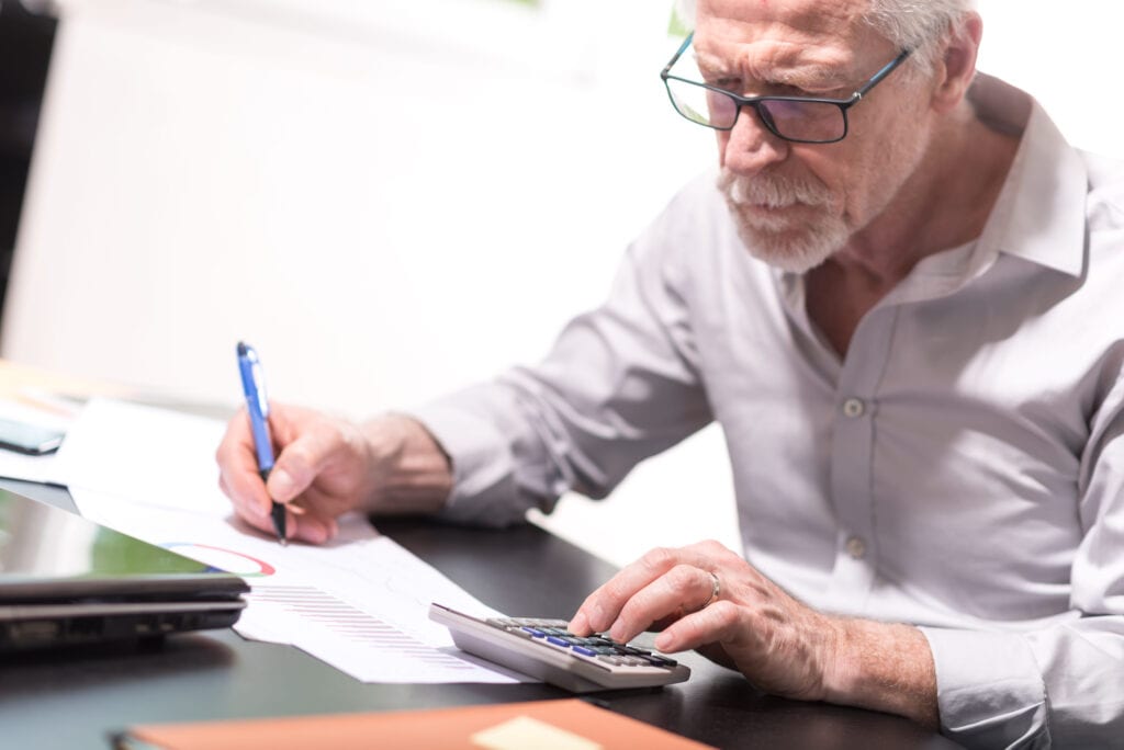 senior taking notes while using calculator gettyimages