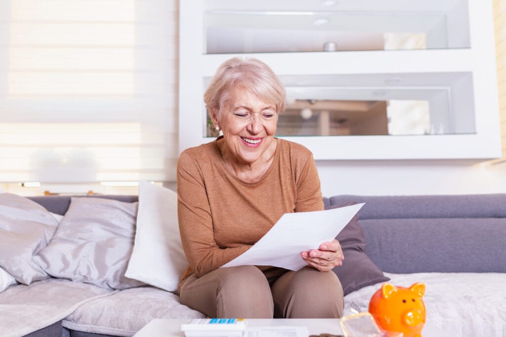 senior woman smiling reading document gettyimages
