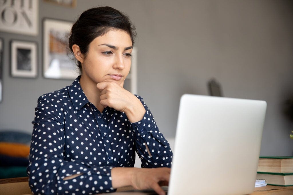 serious person with hand on chin looking at laptop