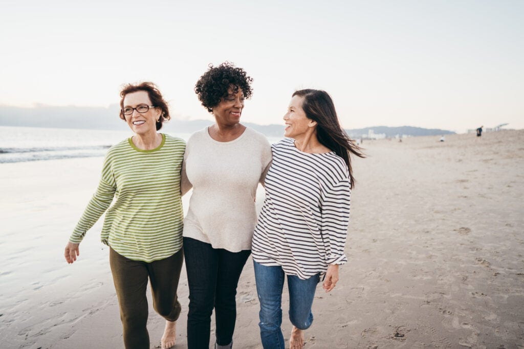 three people walking on the beach and smiling wzx