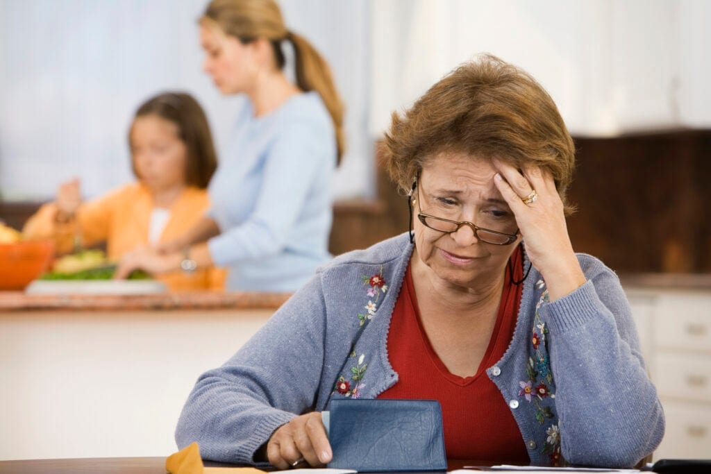 worried senior woman holding checkbook lrfD