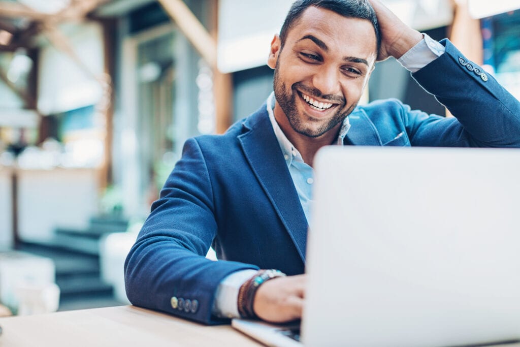excited businessman with hand on head looking at laptop