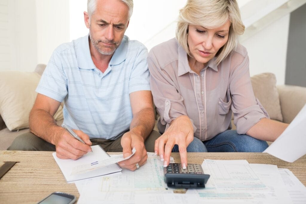 mature couple looking at documents and using calculator bills finances