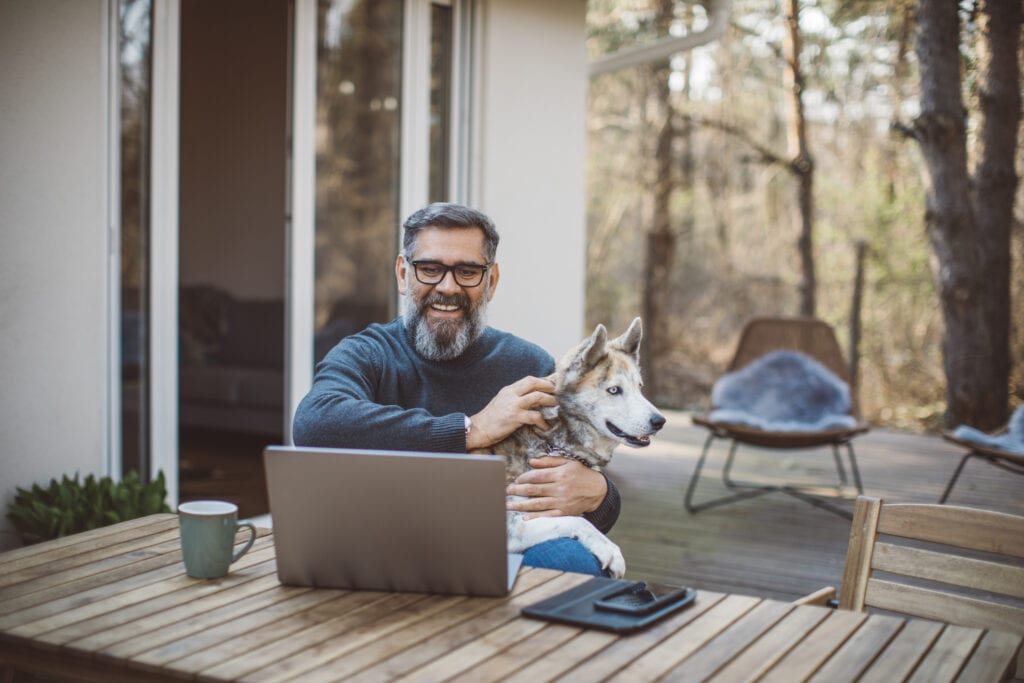 older man at laptop with dog gettyimages