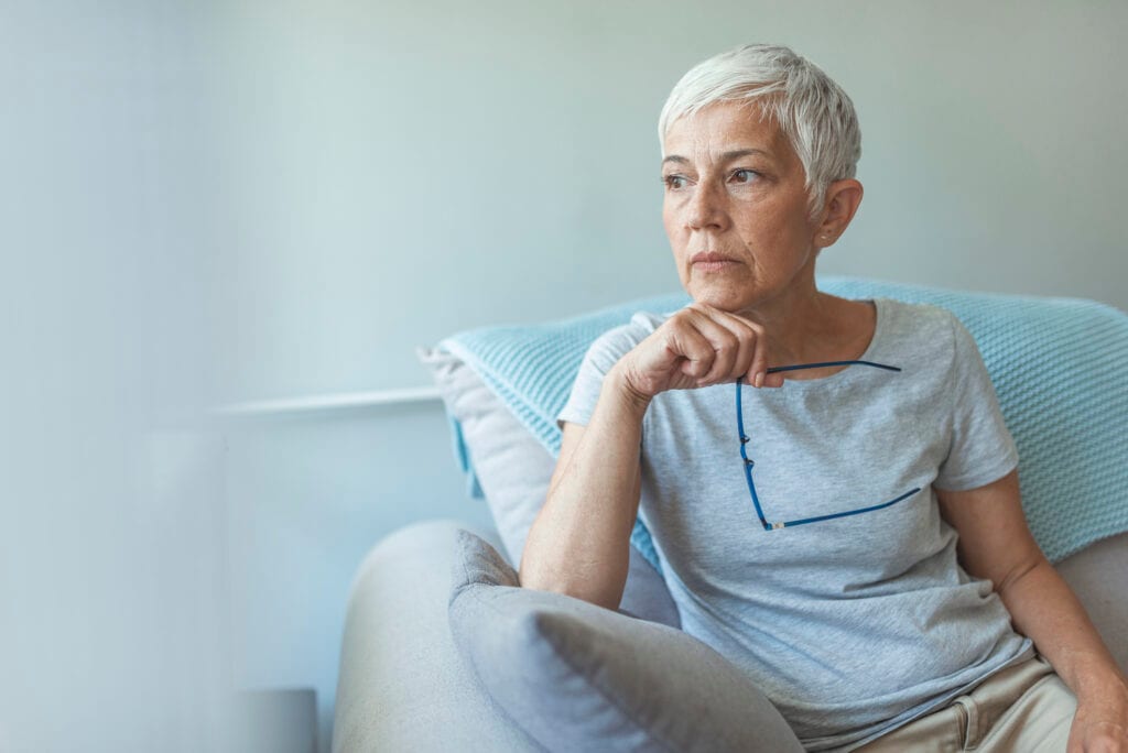 person sitting in a chair holding eyeglasses
