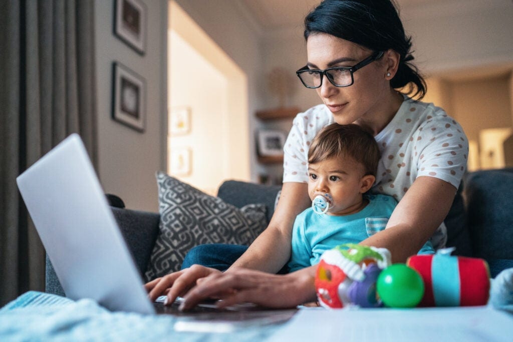 person using laptop with baby in front of them