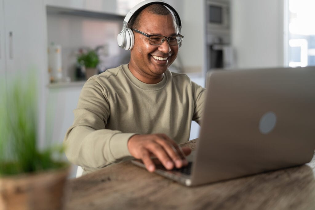 smiling person at laptop wearing headphones gettyimages