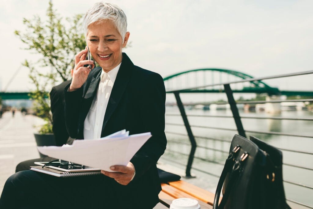 mature senior businesswoman woman on phone looking at documents