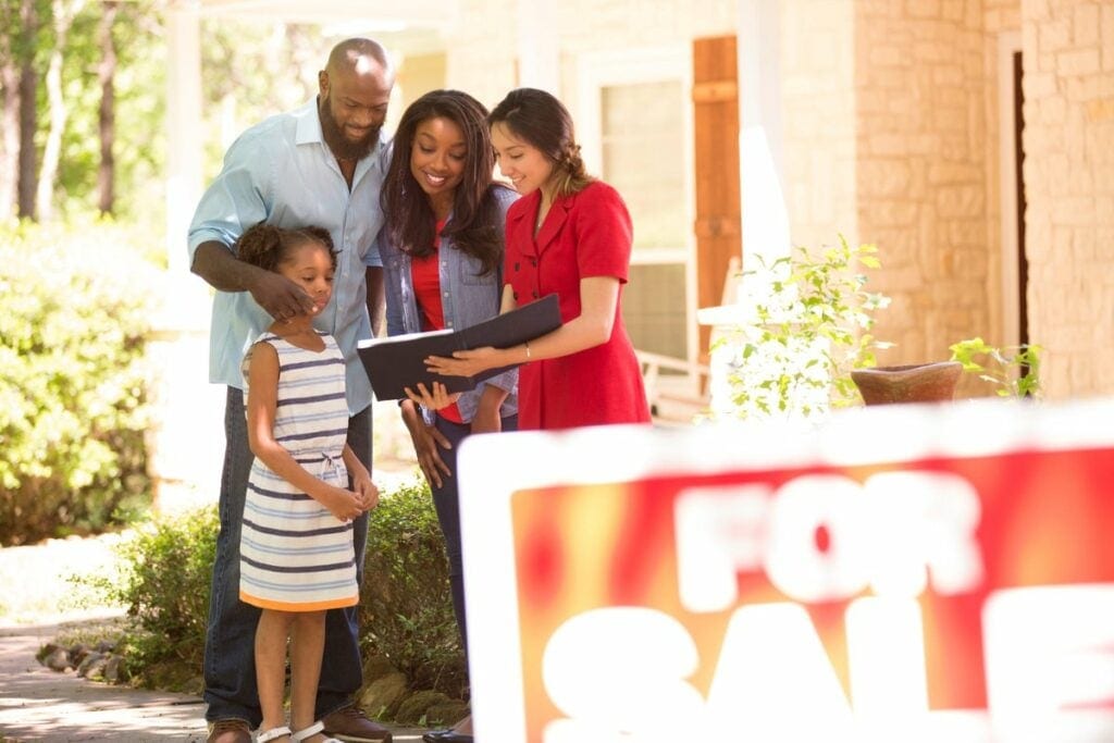 Couple and child in front of home for sale Tp.width