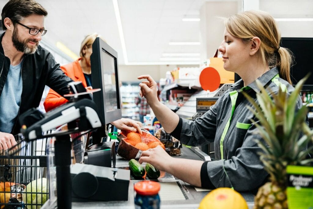 Grocery store employee ringing up customers .width