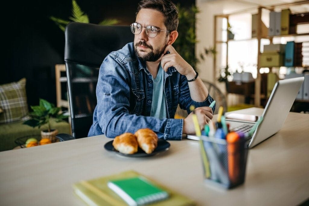 Man using laptop looks away appearing to be i.width mpyFQA