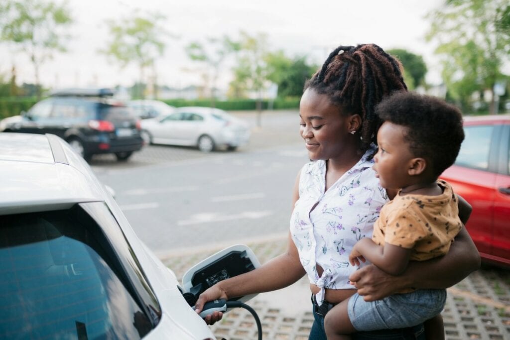 Mother holding her son while charging her ele.width