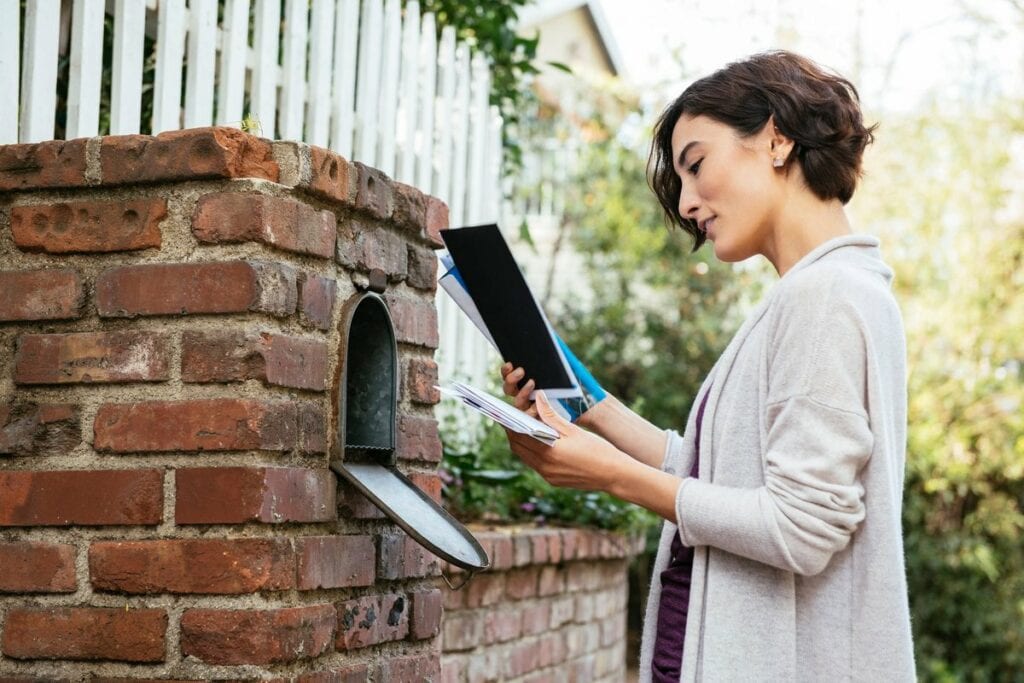 Woman sorting through mail at her mailbox mbL.width