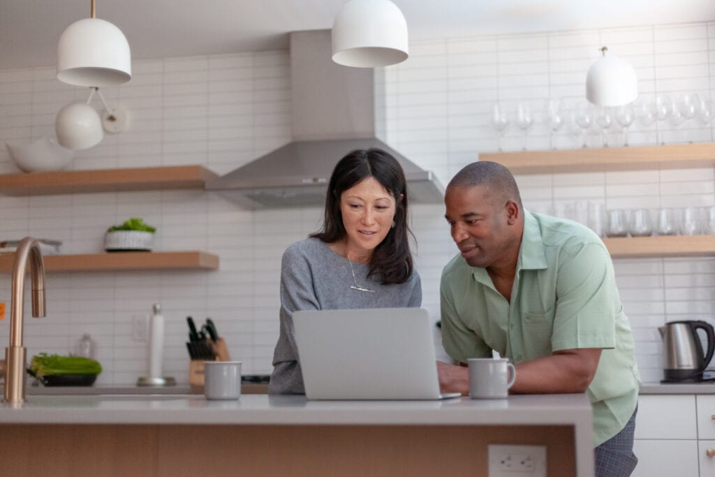 couple staring at computer in kitchen
