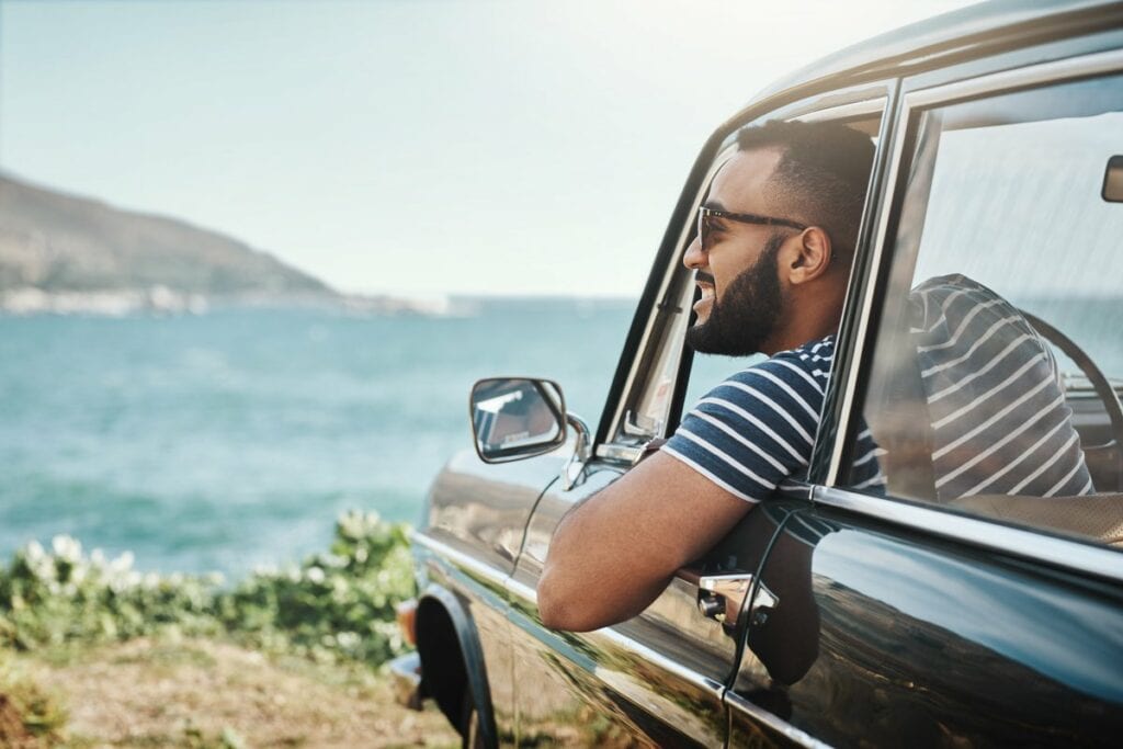 man in car at ocean.width