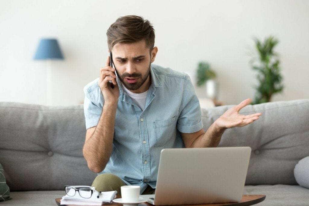 man on couch on phone call near laptop gfF.width .jpg