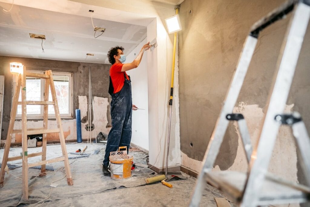 person putting up drywall in home renovation .width