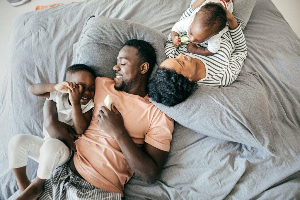 two parents with young kids on bed HxMda.width .jpg