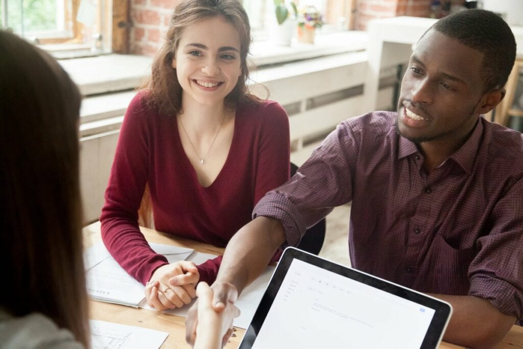 Couple shaking hands over paperwork at a desk.width jzUDgFs.jpg