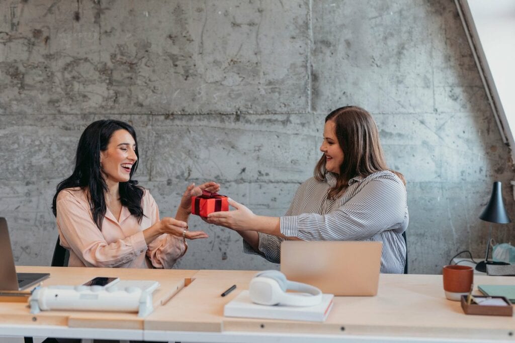 Female gives friend wrapped gift in an office.width JBnNnN.jpg