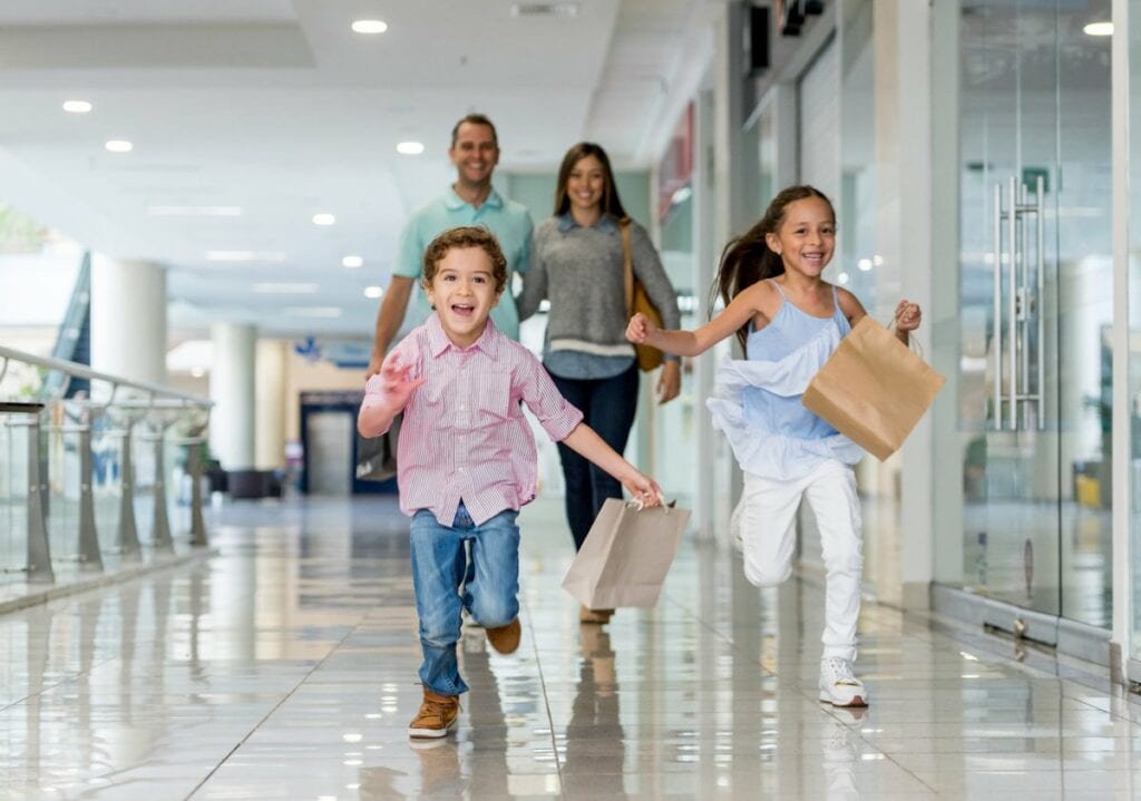 Parents and kids at shopping mall with shoppi.width GYqrug.jpg