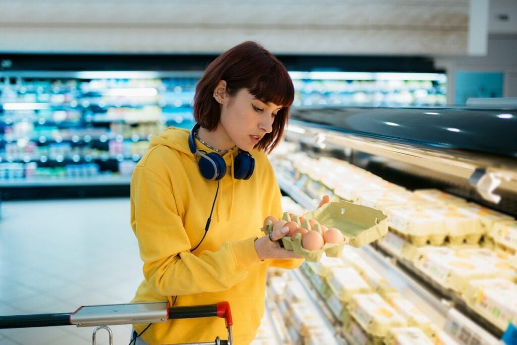 Shopper inspecting a carton of eggs in the gr.width .jpg