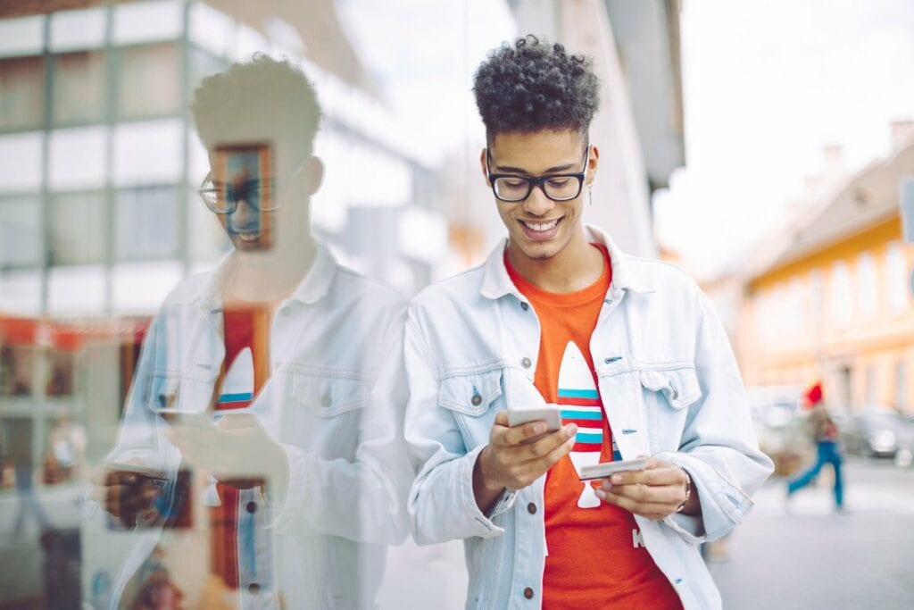 Teen boy using his phone and holding a credit.width .jpg