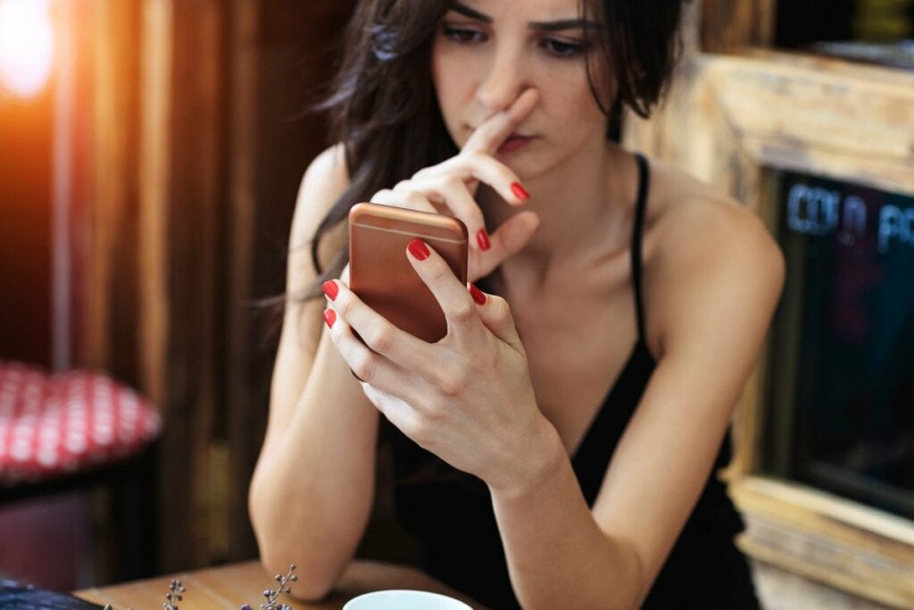 Woman looks skeptically at her cellphone t.width .jpg