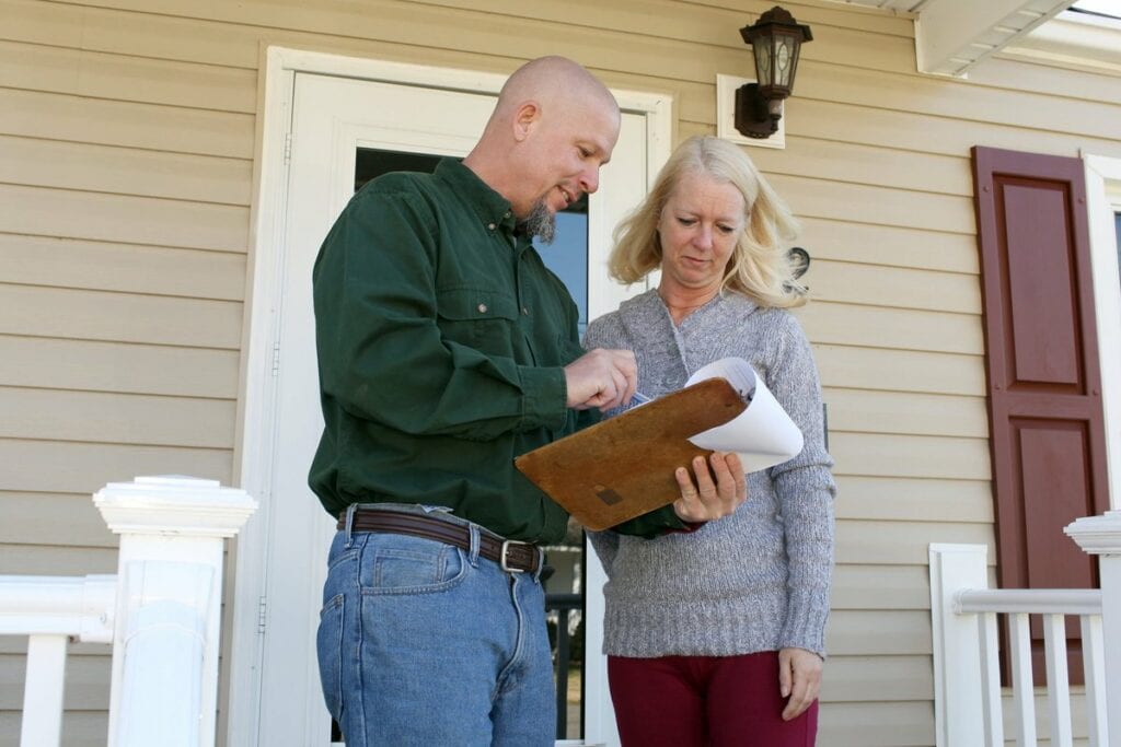 Woman on porch talking to man with clipboard .width .jpg