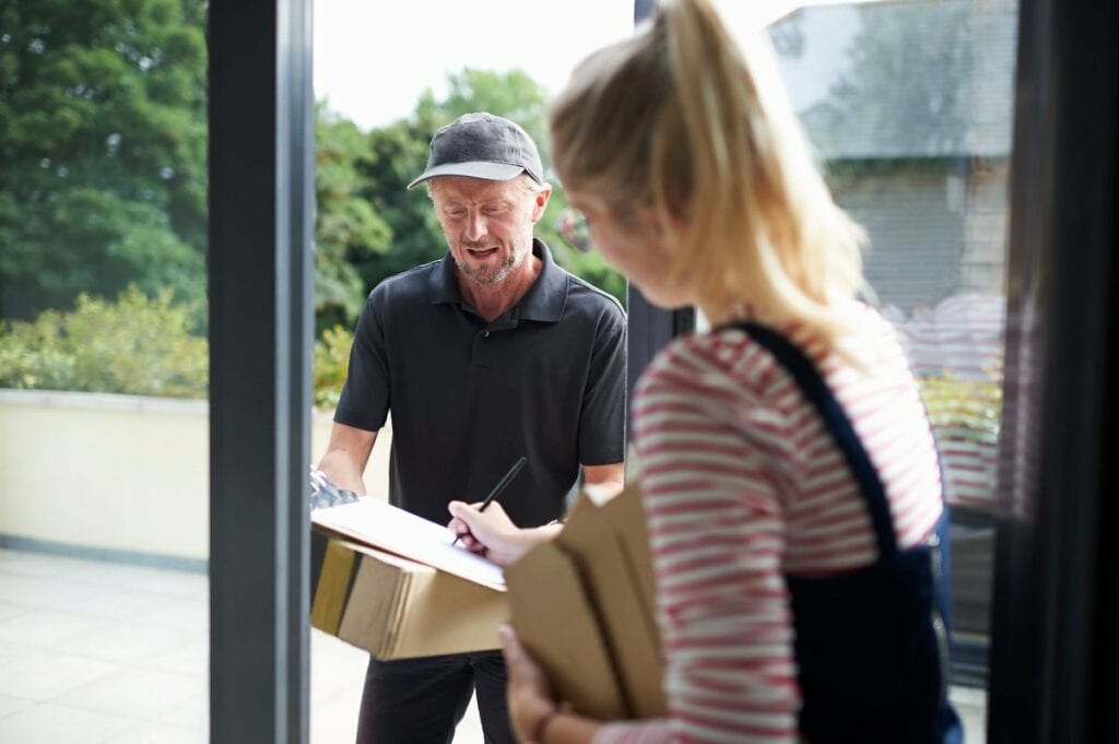 Woman signing for packages with a delivery pe.width VWyGgX.jpg