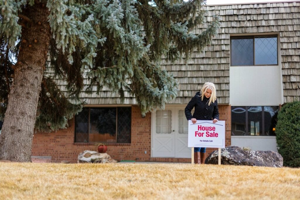 person in front of house with for sale sign S.width .jpg