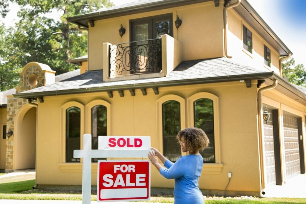 person putting sold sign in front of house T.width .jpg