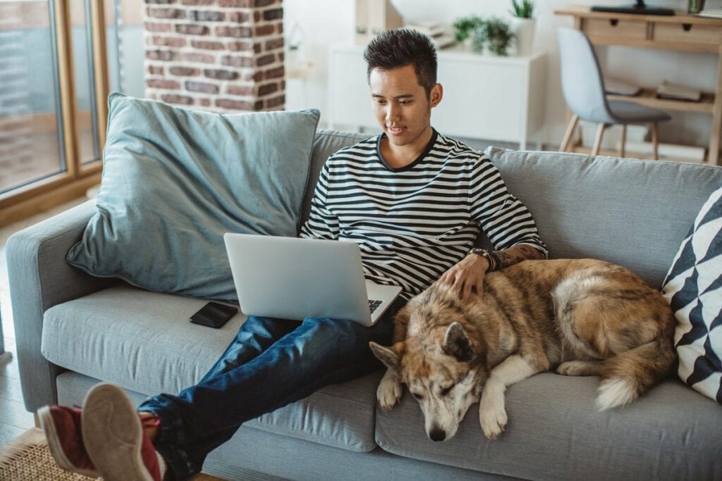 young man on laptop on couch with dog QRysiD.width .jpg