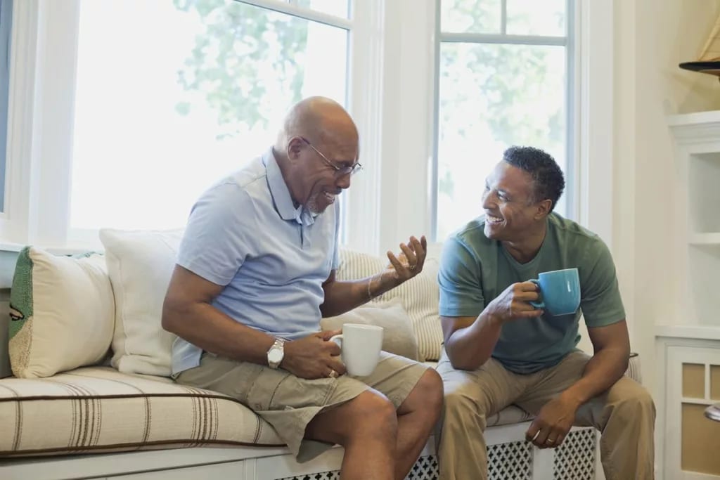 Cheerful father and son having coffee on sofa.width .jpg
