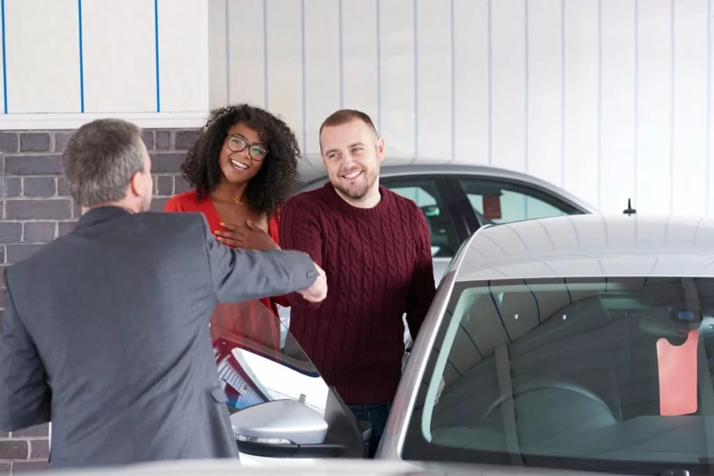 Couple shakes hand with a car salesman near a.width DnSBi.jpg