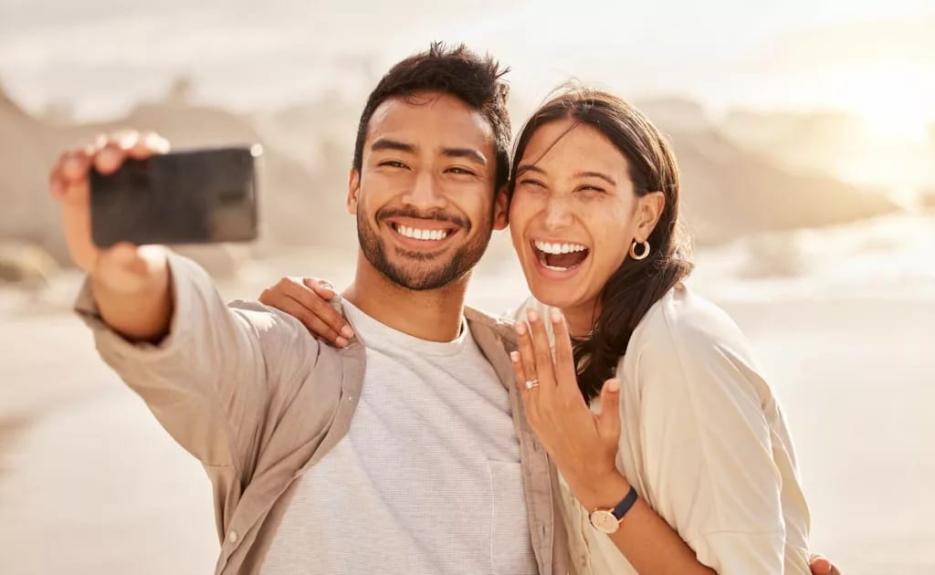 Couple smiling and taking selfie with engagem.width .jpg