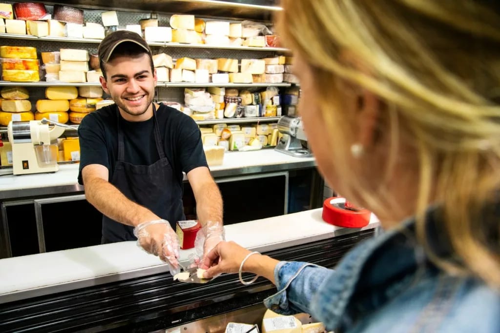 Employee handing sample of cheese to woman sh.width QAGKAOI.jpg