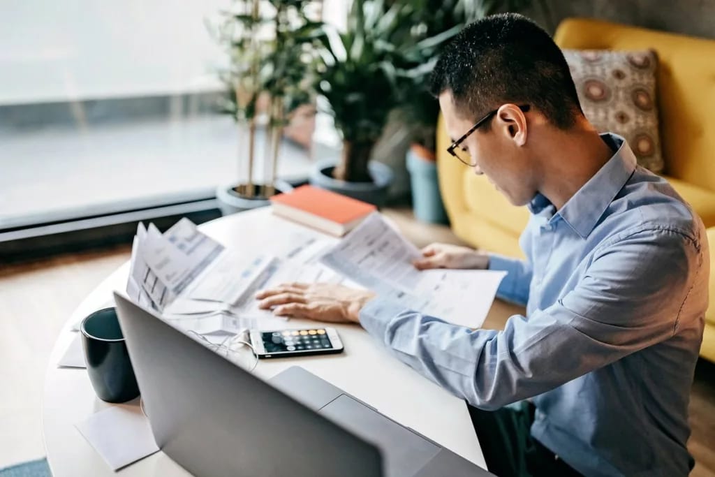MAn using a calculator and looking over docum.width bFwUjX.jpg