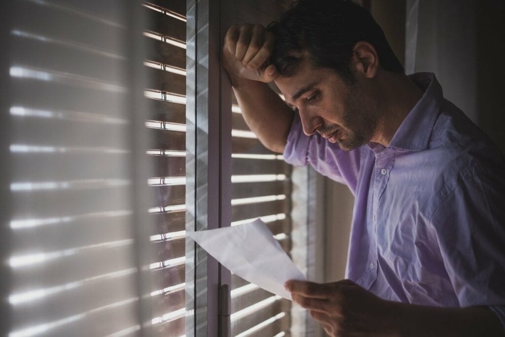 Man looks saddened by paper that hes reading .width .jpg