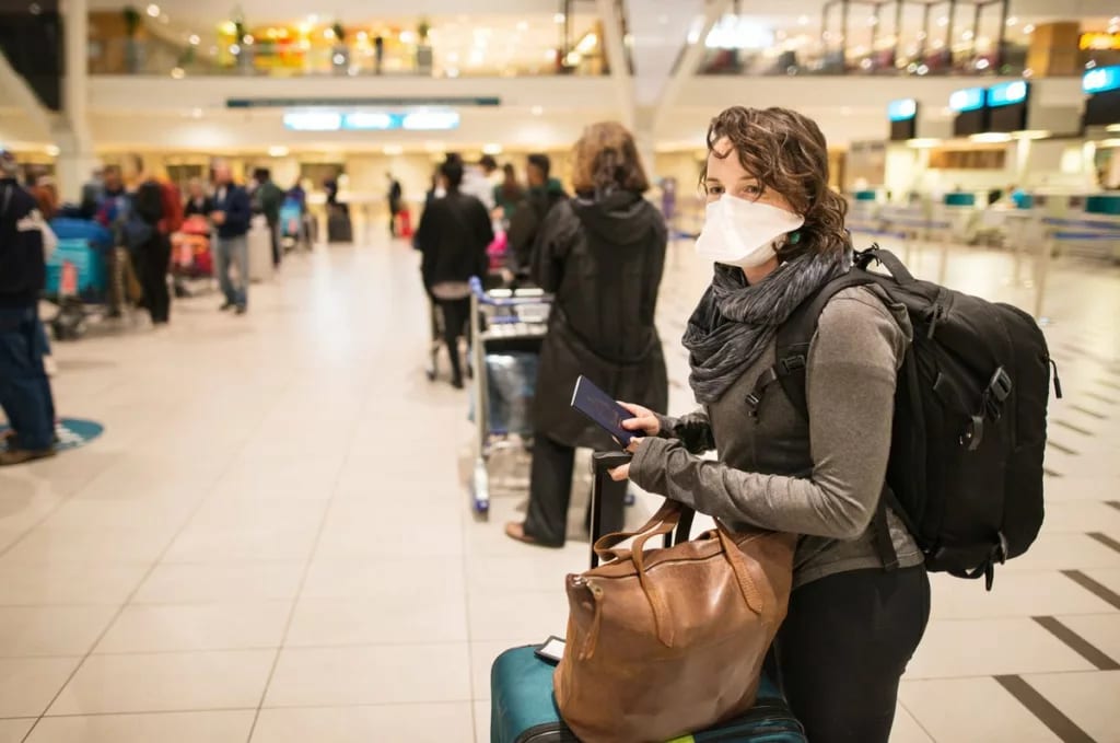 Masked woman with luggage waiting in an airpo.width ogAmB.jpg