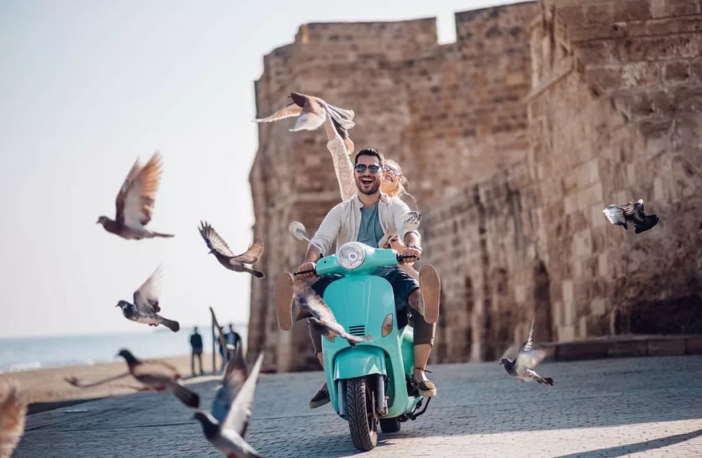 Tourists riding motorized scooter in old euro.width DbAtPjZ.jpg
