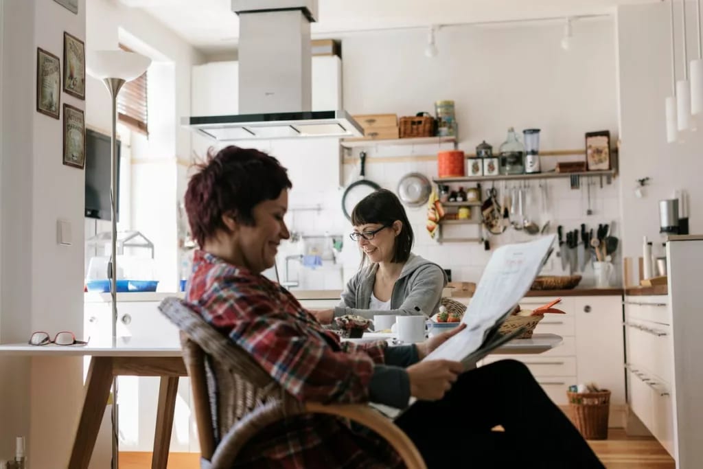 Two people in a kitchen reading the news toJ.width .jpg