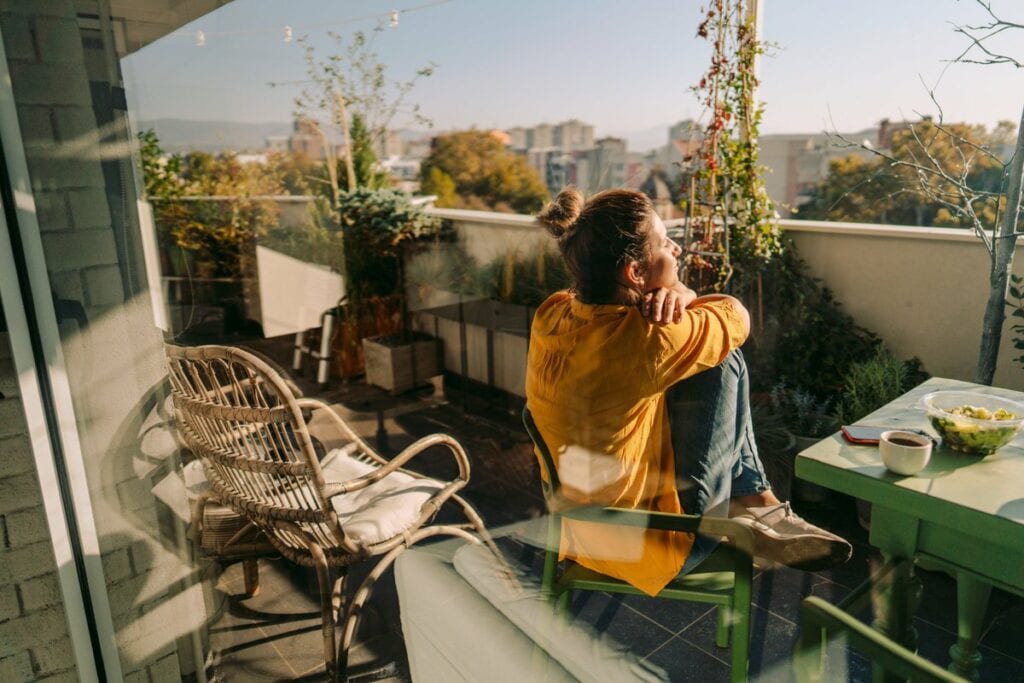Woman sitting outside on her condo balcony Hq.width .jpg