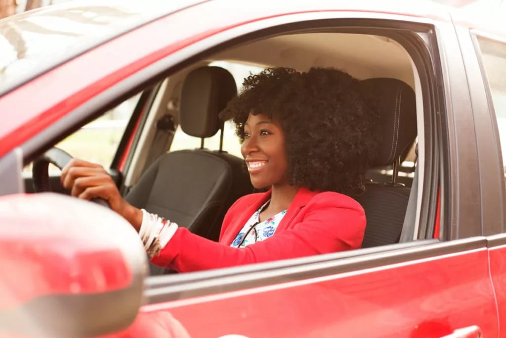 Woman smiling as she drives a red vehicle Db.width .jpg