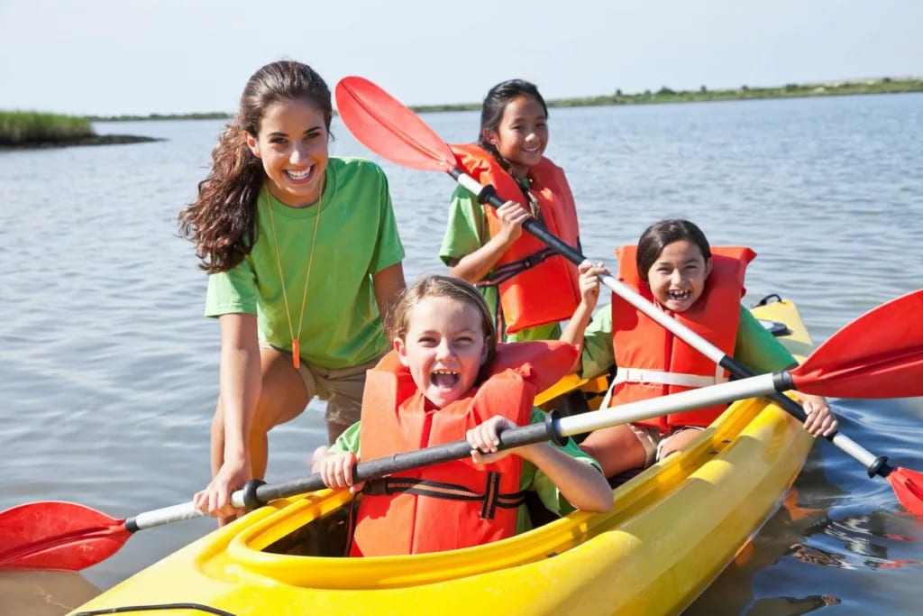 Young adult girl helping kids in a kayak FaRw.width .jpg